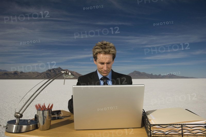Businessman on salt flats looking at laptop, Salt Flats, Utah, United States. Date : 2007
