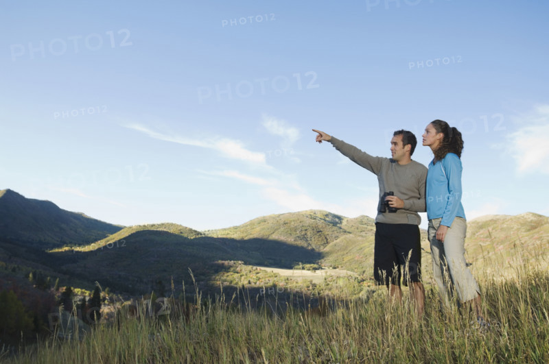 Couple holding binoculars and pointing, Utah, United States. Date : 2007