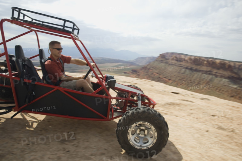 Man in off-road vehicle on rock formation. Date : 2007