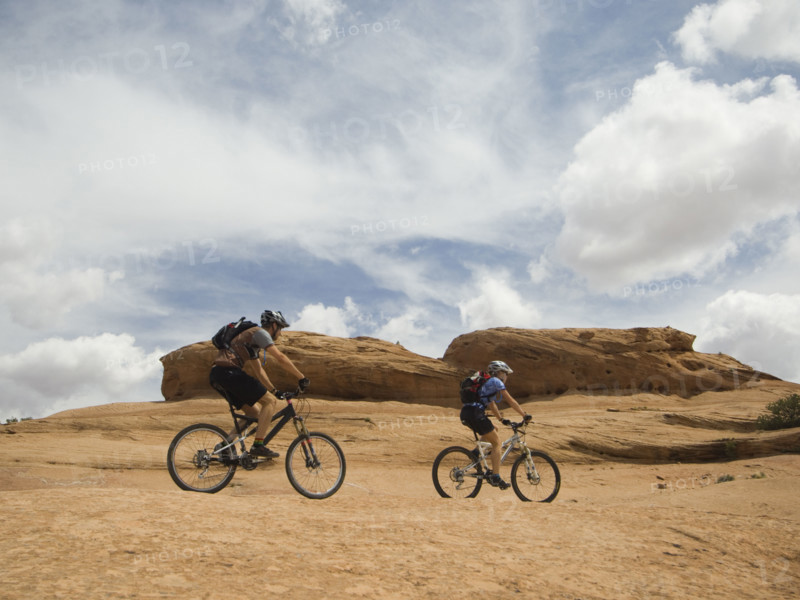Couple riding mountain bikes in desert. Date : 2007