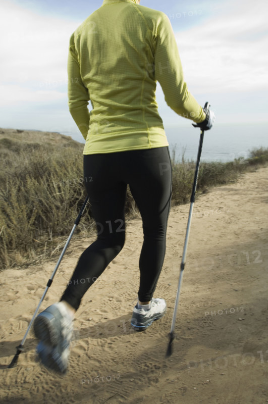 Hispanic woman pole walking along coast in California, United States. Date : 2007