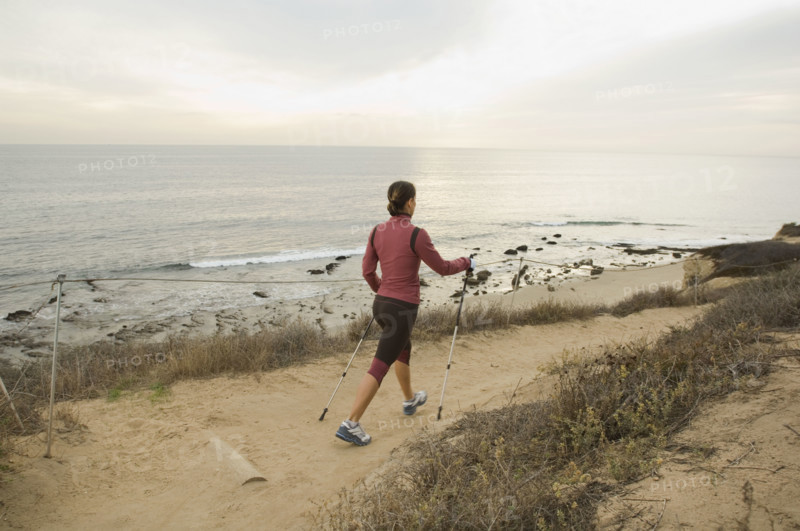 Hispanic woman pole walking along coast in California, United States. Date : 2007
