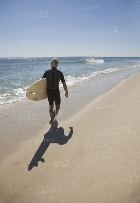 Man carrying surfboard at beach.