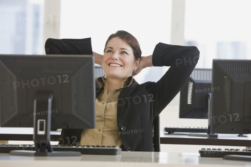 Businesswoman with hands behind head.