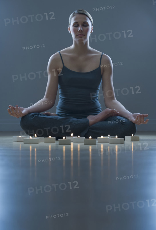 Woman meditating next to candles.