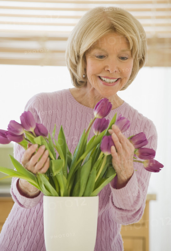Senior woman arranging flowers.