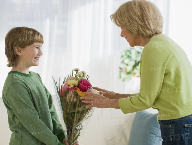 Grandson giving flowers to grandmother.