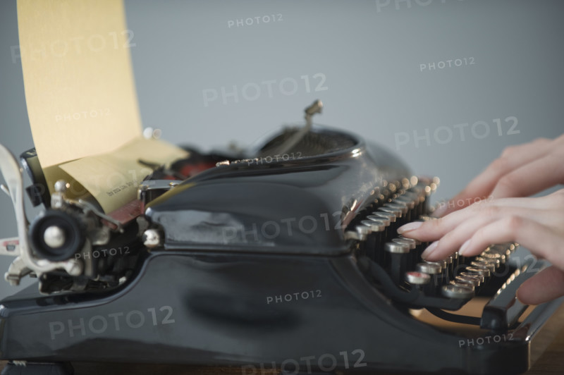 Woman typing on antique typewriter.