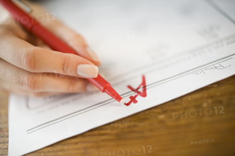 Teacher writing A plus grade on worksheet.