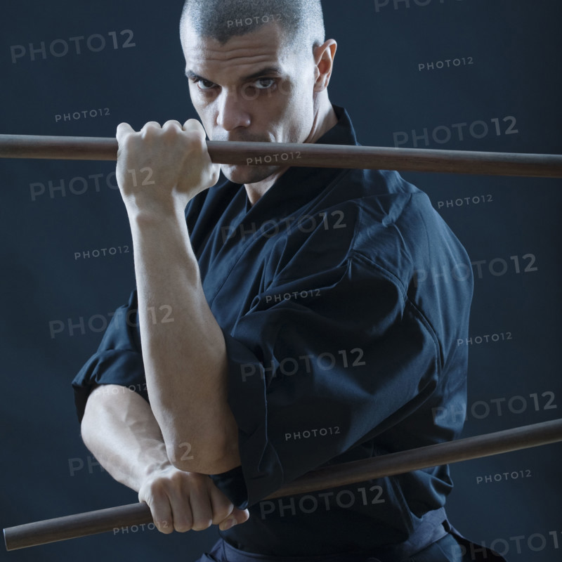 Hispanic male holding sticks in fighting stance.