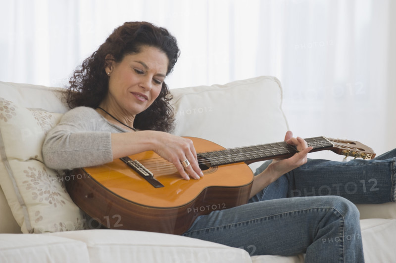 Hispanic woman playing guitar.