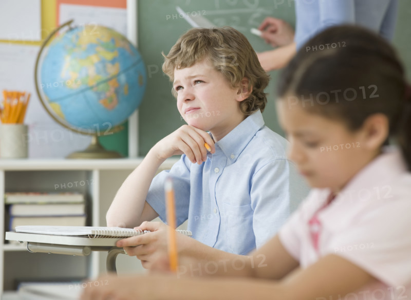 Boy thinking at school desk.