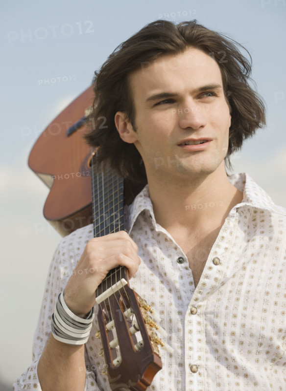 Man holding guitar on shoulder.