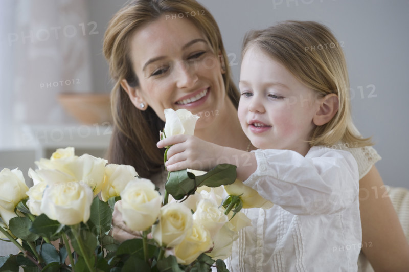 Mother watching daughter arrange flowers.