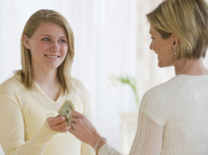 Mother giving money to teenaged daughter.