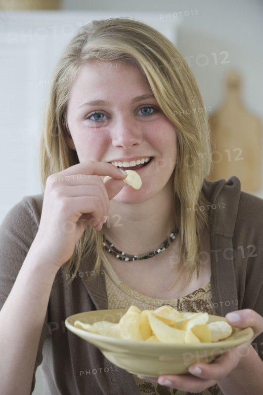 Teenaged girl eating potato chips.