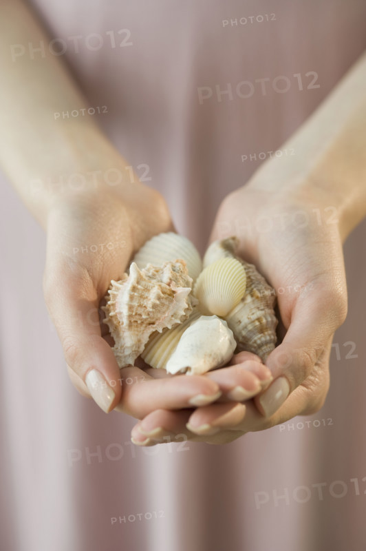 Woman holding handful of seashells.