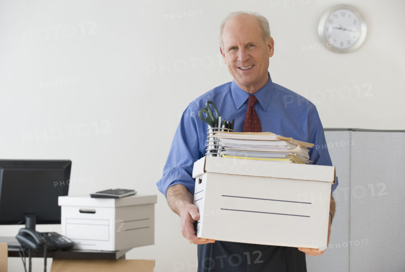Senior businessman carrying box and office supplies.
