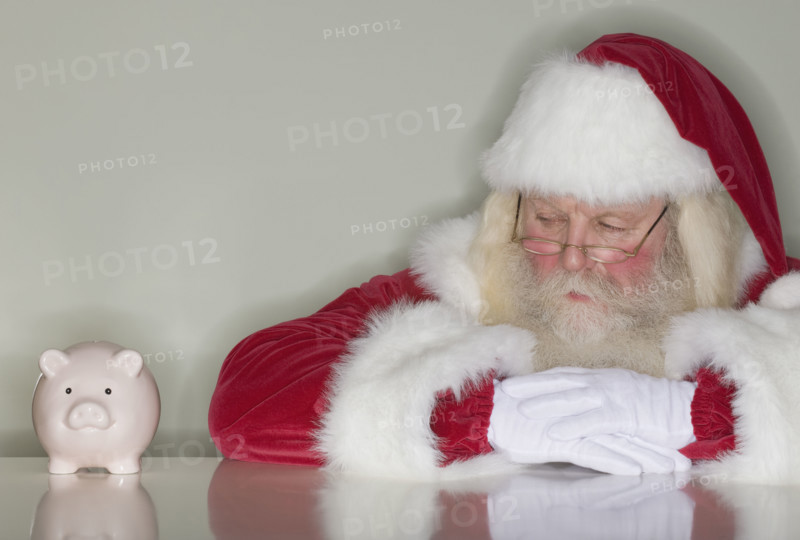 Santa Claus looking at piggy bank.