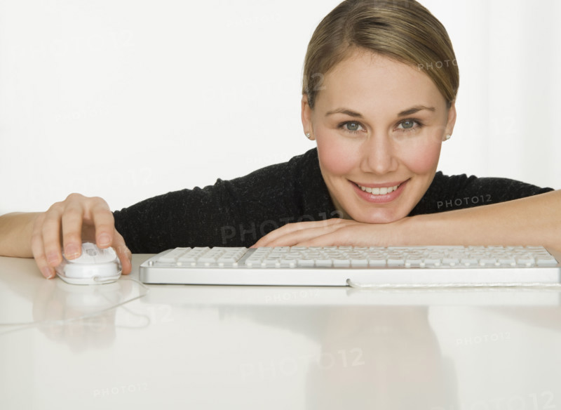 Woman leaning on table next to keyboard.
