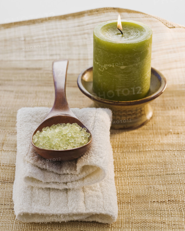 Bath salt in spoon next to candle.