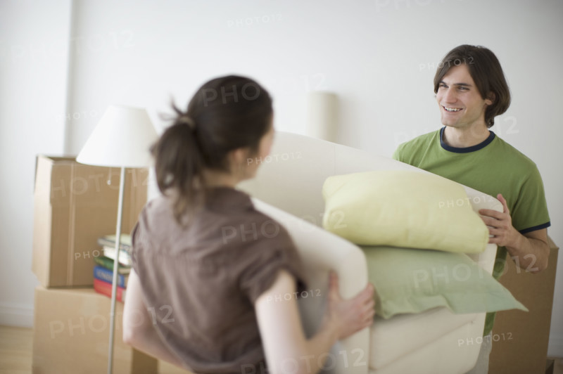 Couple carrying bedding in new house.