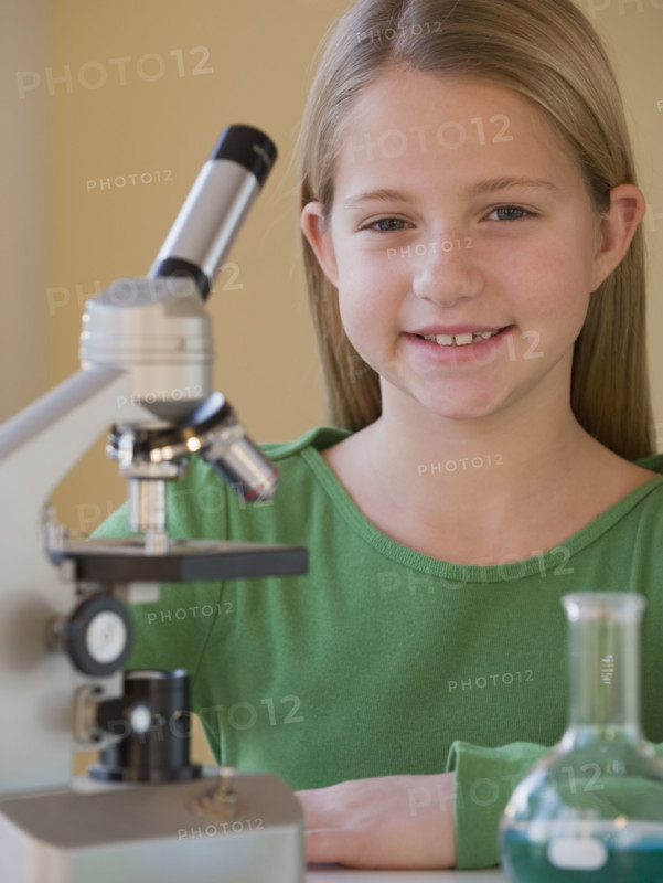 Girl in science class next to microscope.