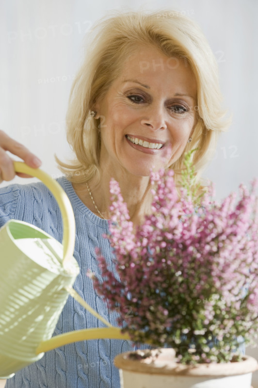 Senior woman watering plant.