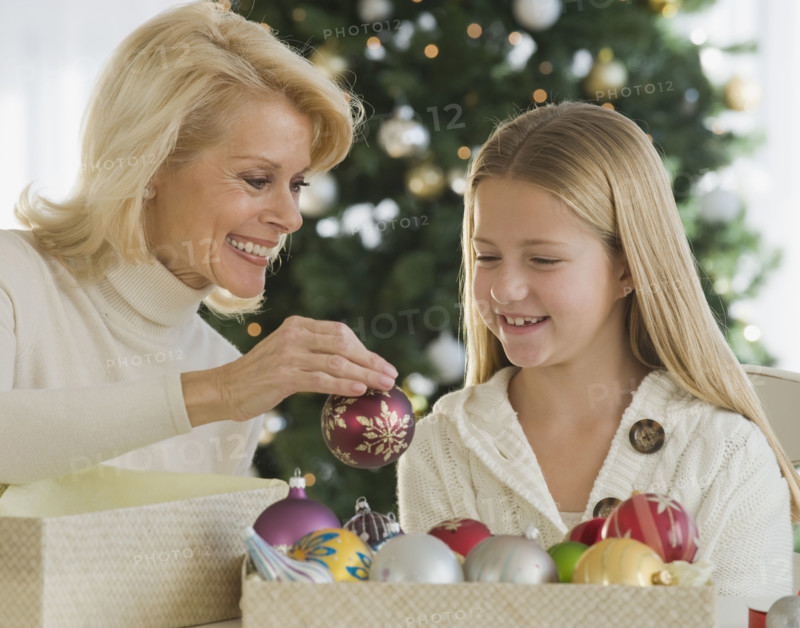 Grandmother and granddaughter looking at Christmas ornaments.