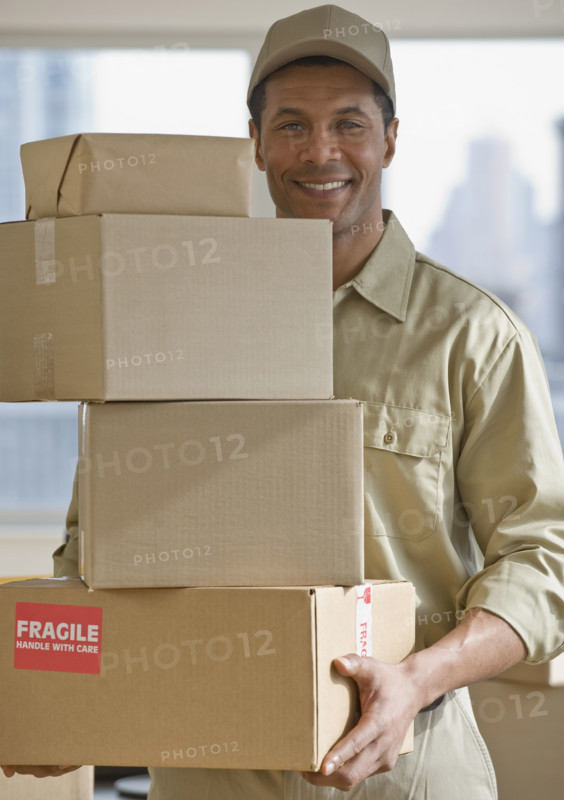 African delivery man carrying stack of packages.
