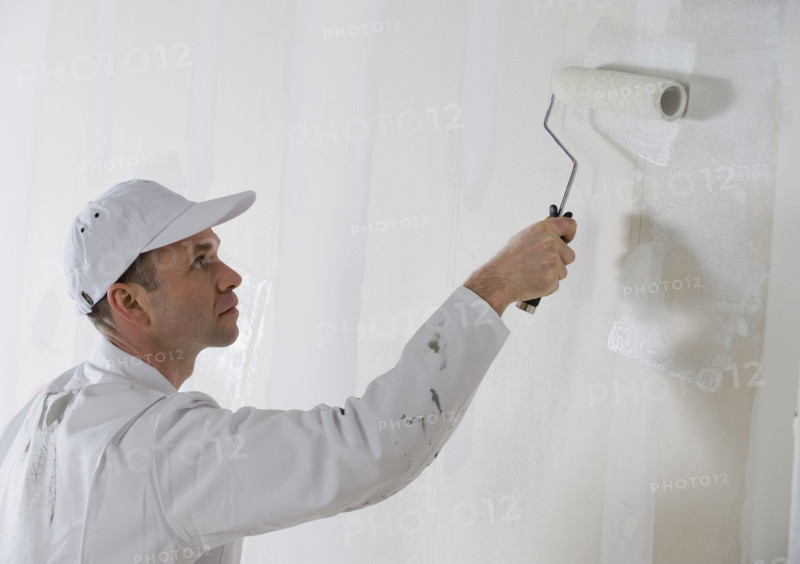 Male painter painting with paint roller.