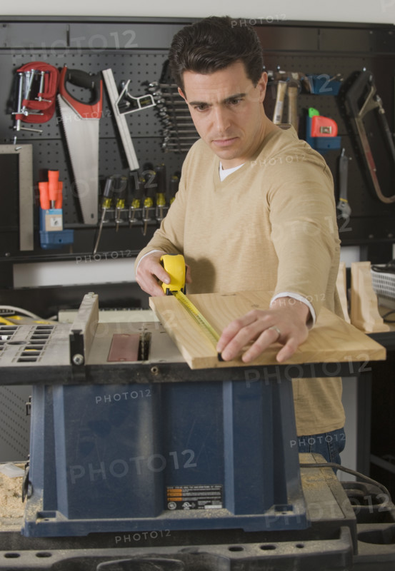 Male woodworker measuring piece of wood.