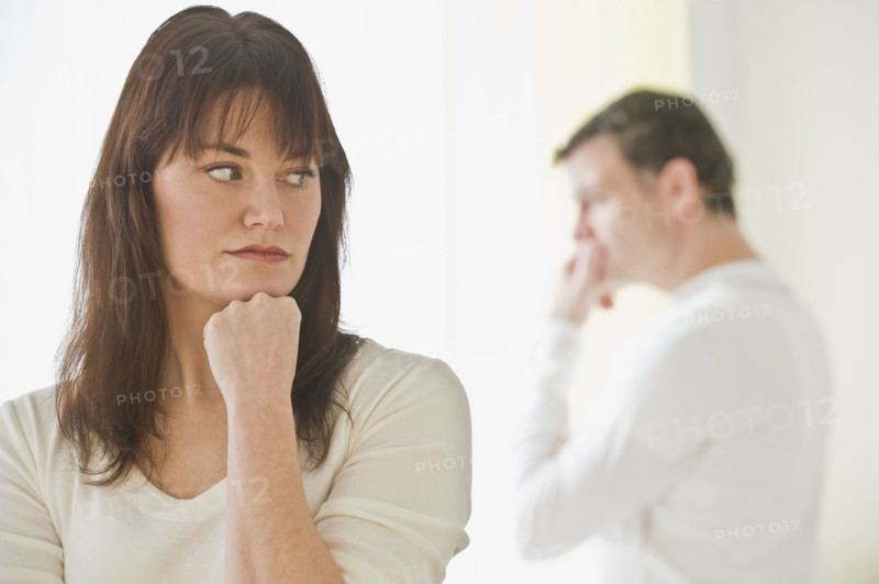 Upset woman with husband in background.