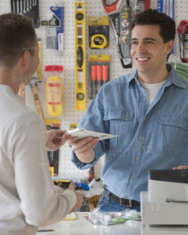 Hardware store sales clerk handing over purchase.
