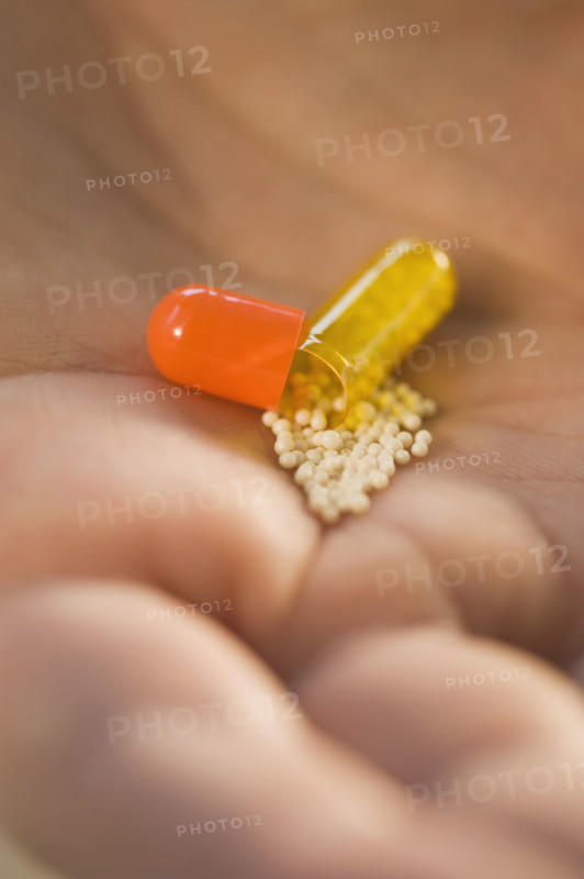 Close up of open medication capsule in man’s hand.