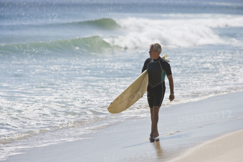 Man carrying surfboard at beach.