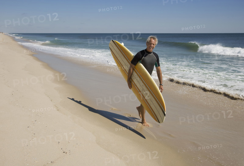 Man carrying surfboard at beach.
