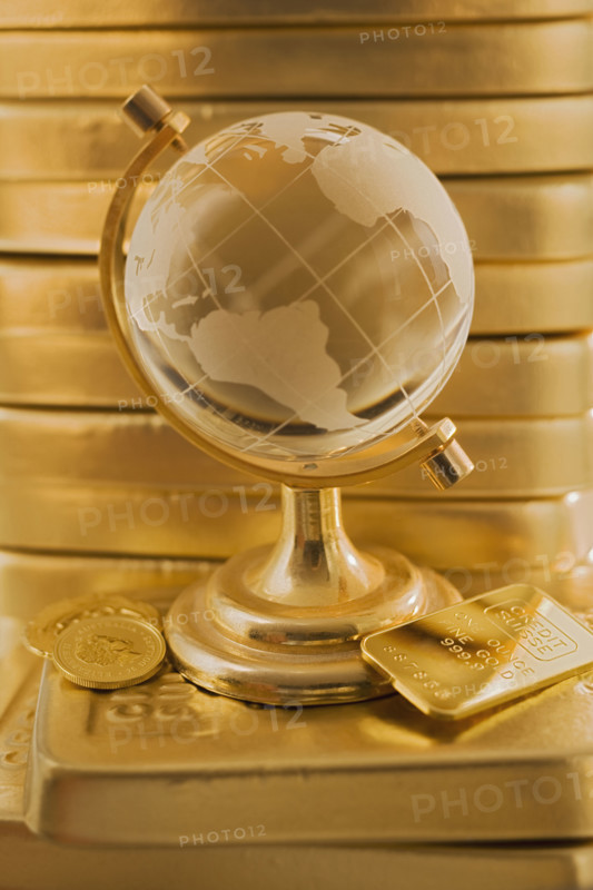 Globe in front of stack of gold bars.