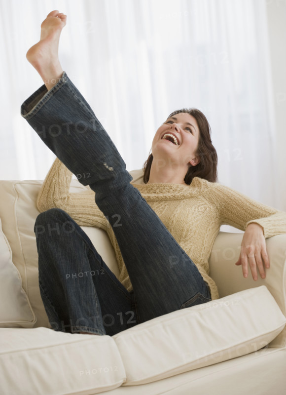 Woman kicking leg on sofa.