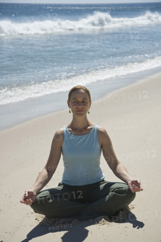 Woman practicing yoga at beach.