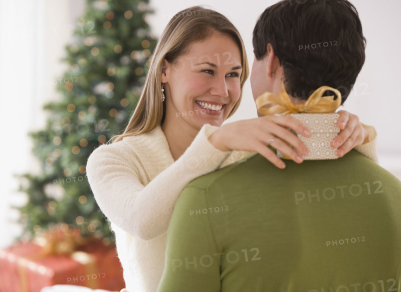Woman holding gift and hugging husband.
