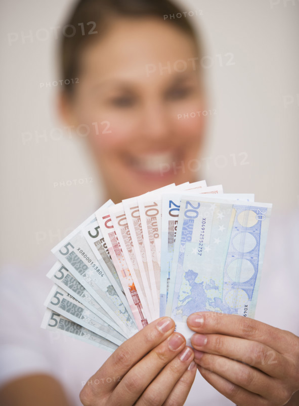 Woman holding fanned out euro banknotes.