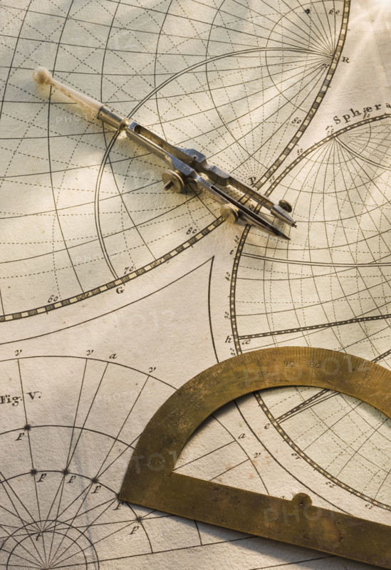 Protractor and drafting compass on antique map.
