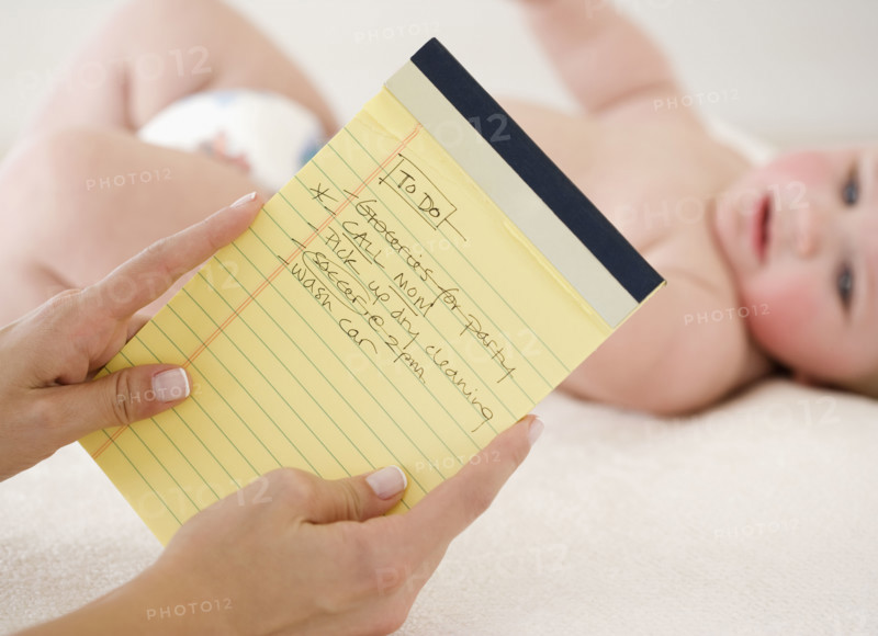 Mother looking at To Do list in front of baby. Date : 2008
