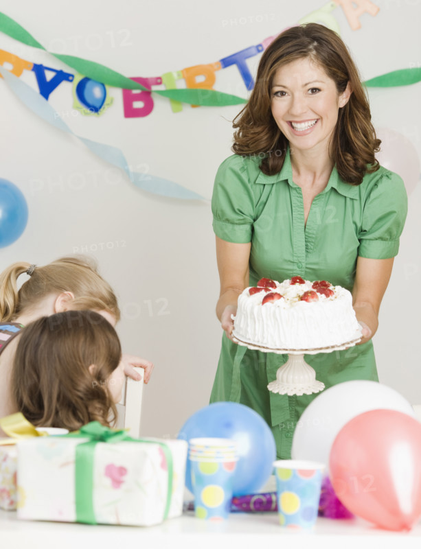 Mother holding birthday cake at party. Date : 2008