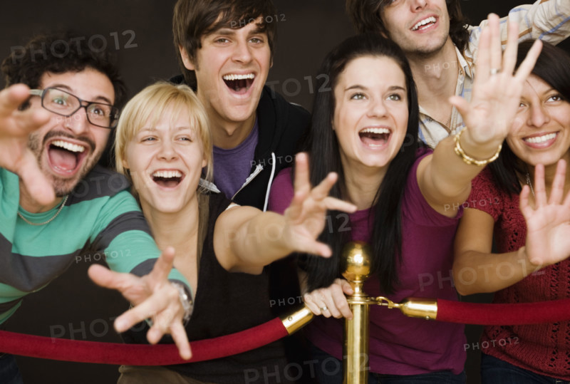 Group of people reaching across velvet rope. Date : 2008