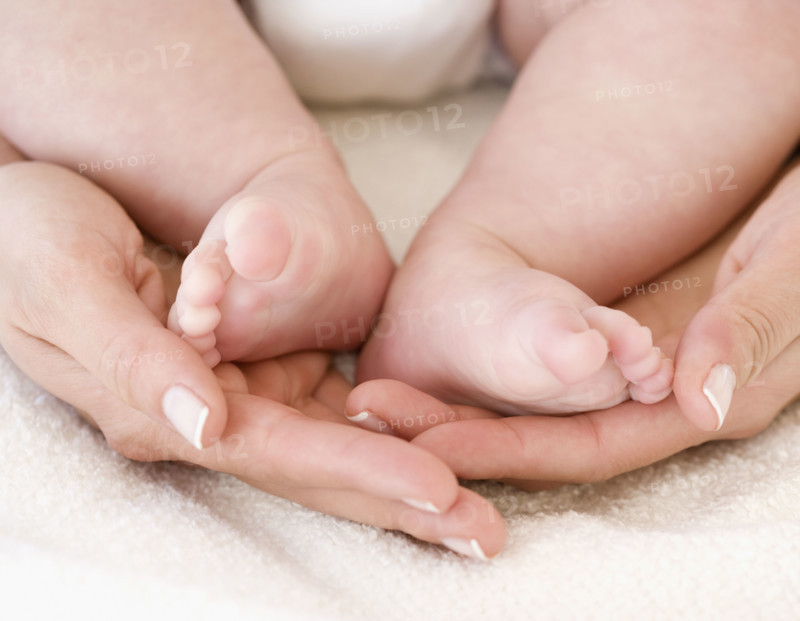 Close up of mother’s hands and baby’s feet. Date : 2008
