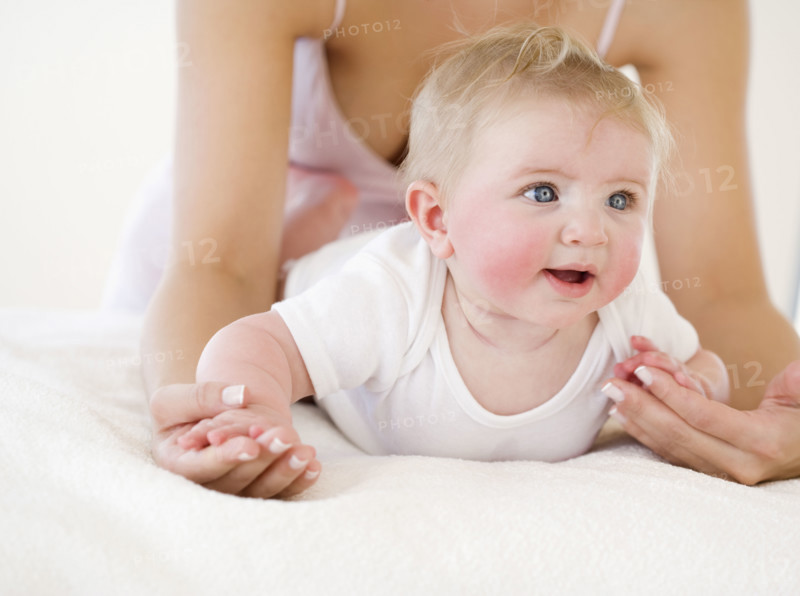 Mother leaning over baby on bed. Date : 2008