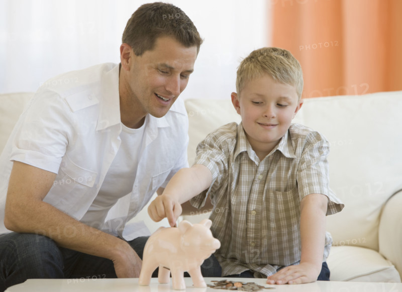 Father and son putting money in piggy bank.