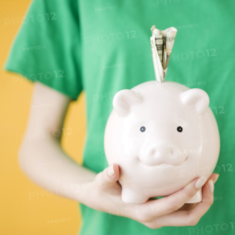 Woman holding piggy bank with money in slot. Date : 2008